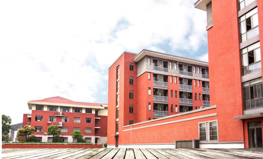 Red brick school buildings under a partly cloudy sky